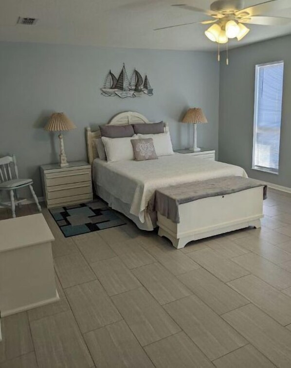 A bedroom with a bed, nightstands, a desk, and a chair.