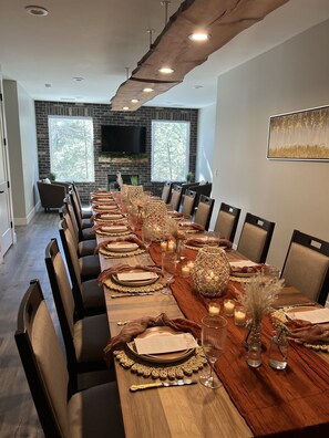 Una larga mesa de comedor dispuesta para una cena formal, con sillas, velas y centros de mesa decorativos.