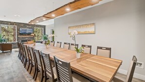A spacious dining area with a long wooden table, multiple chairs, and a modern ceiling design. - "The Ponderosa"-Gathering Tree's Deluxe Group Stay with private KING suites (Flagstaff)