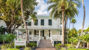 A white building with a porch and a sign that reads "Coconut Beach Resort."