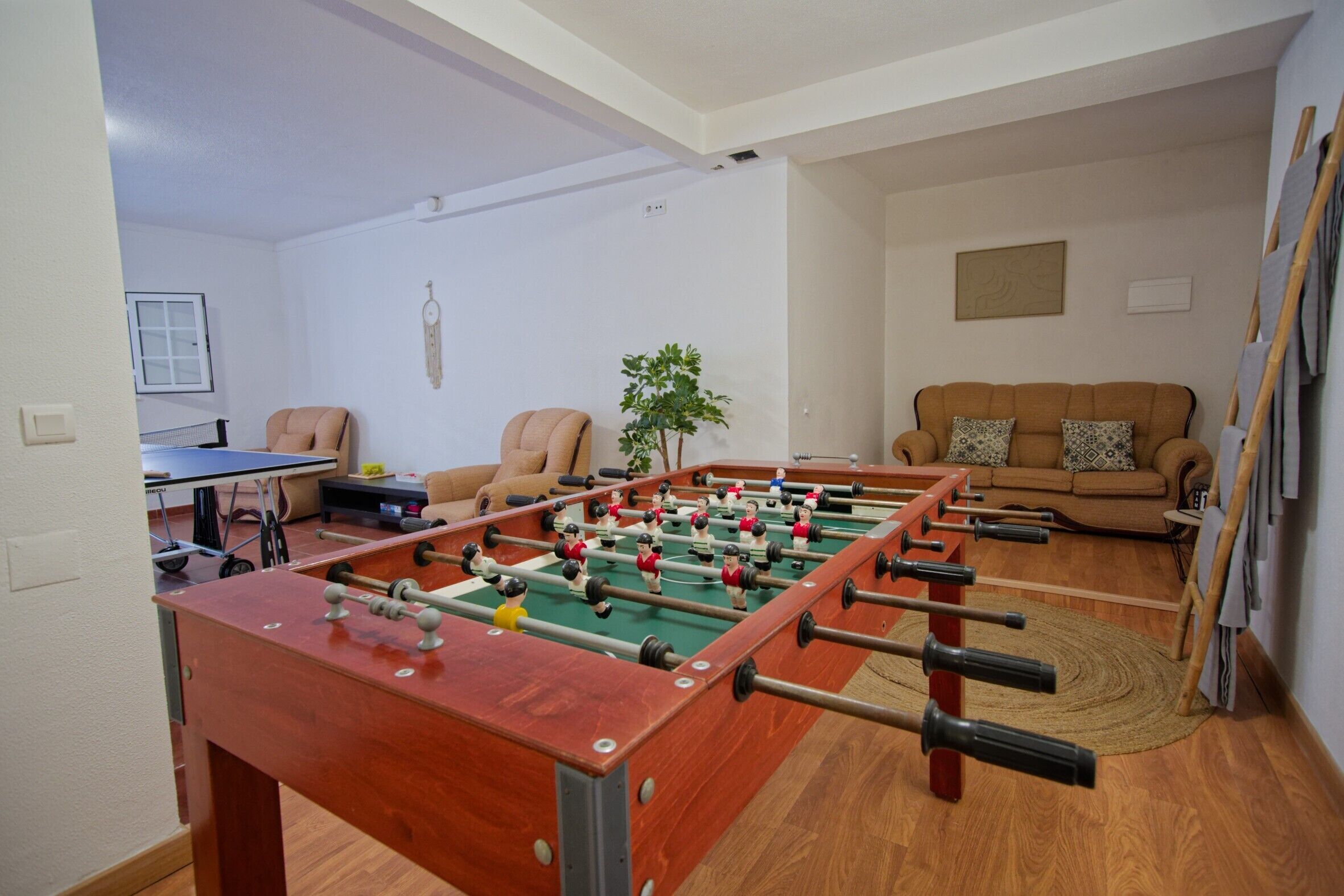 Une pièce comprenant une table de baby-foot, un canapé, une table basse et une table de ping-pong.