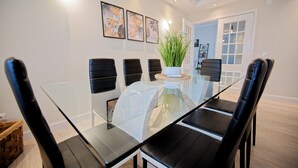 A modern dining room with a glass table, black chairs, and decorative wall art. - Holiday Home Villa As Cumadres with Mountain View, Pool, Garden & Wi-Fi (Azeitão)