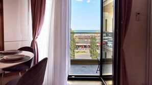 Una habitación con una mesa de comedor dispuesta para dos personas, vista al mar y un supermercado a través de un ventanal grande.