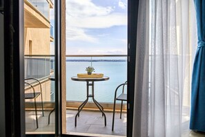 A balcony with a table and chairs, overlooking a body of water and a distant shoreline. - Apartamente Exterior (Constanta)