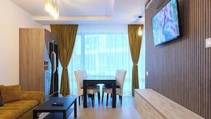 Una sala moderna con un sofá, una mesa de centro, un televisor montado en la pared y un comedor con una mesa y sillas.
