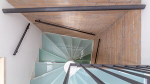 Un escalier en colimaçon avec des panneaux de verre et un mur de briques.
