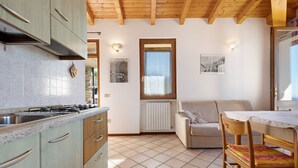 A kitchen with a stove, cabinets, and a dining area with a table and chairs. - Holiday Apartment 'Rustico Spagnol 2' with Lake View, Pool & Wi-Fi (Tignale)