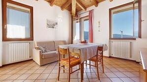 A room with a wooden ceiling, a dining table with chairs, a sofa, and large windows with curtains. - Holiday Apartment 'Rustico Spagnol 2' with Lake View, Pool & Wi-Fi (Tignale)