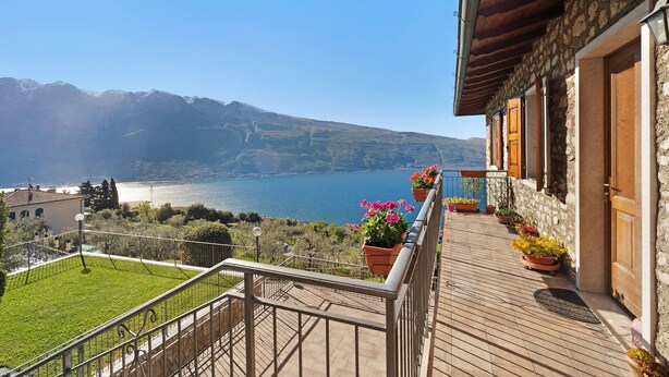 A balcony with a view of a lake and mountains, stone walls, and wooden doors. - Holiday Apartment 'Rustico Spagnol 2' with Lake View, Pool & Wi-Fi (Tignale)
