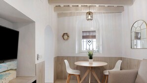 A corner room with a TV, a round table with chairs, a potted plant, and a window with blinds. - Apartment "Cobarrubias" with Shared Terrace & Wi-Fi (Vejer)