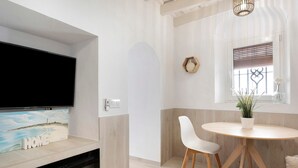 A modern kitchen with a flat-screen TV, a wooden island, and a dining area with a round table and chairs. - Apartment "Cobarrubias" with Shared Terrace & Wi-Fi (Vejer)