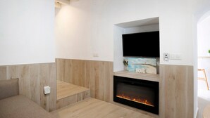 A modern living room with a fireplace, a flat-screen TV mounted above it, and a wooden accent wall. - Apartment "Cobarrubias" with Shared Terrace & Wi-Fi (Vejer)