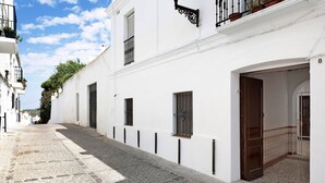 A narrow cobblestone street flanked by white buildings with balconies, a wooden door, and a patterned floor. - Apartment "Cobarrubias" with Shared Terrace & Wi-Fi (Vejer)