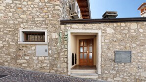 A stone building with a wooden door, a small window with bars, and a metal doorbell. - Holiday Apartment 'Rustico Spagnol 4' with Lake View, Pool & Wi-Fi (Tignale)