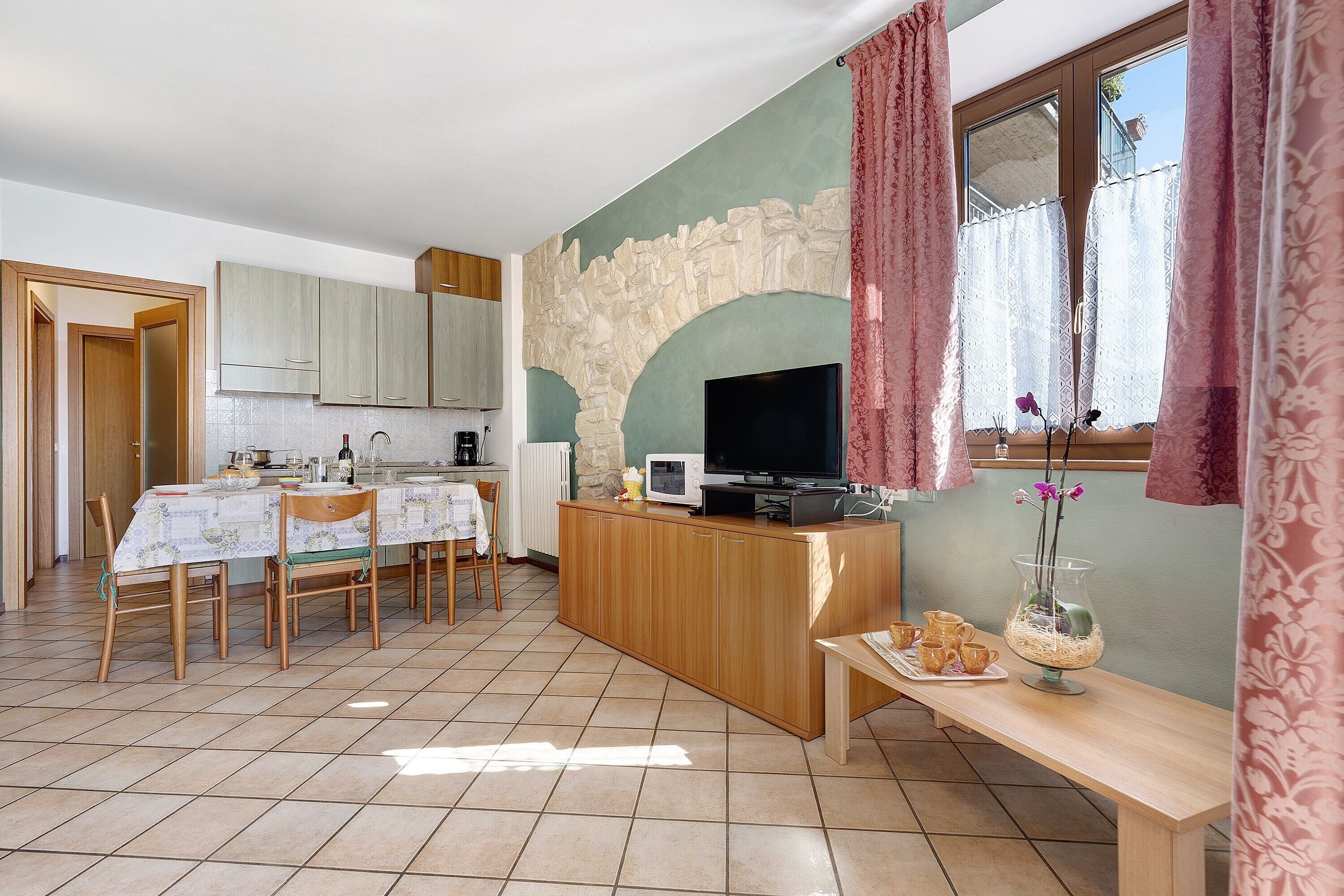 Ein Essbereich mit Tisch, Stühlen, einem Fernseher und einer dekorativen Vase.