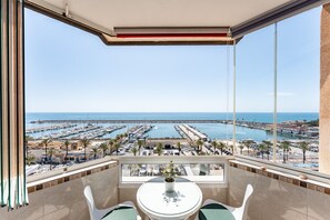 A balcony with a table and chairs, overlooking a marina with boats and a pier.