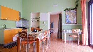 A kitchen with orange cabinets, a dining table with chairs, a map on the wall, and a window with curtains. - Holiday Home 'I Colori di Civico 19' with Terraces & Wi-Fi (Galatina)