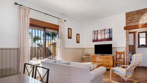 A living room with a sofa, TV, wooden cabinet, and a dining table. - Vacation Home "Casa La Vigía" with Private Pool, Private Terraces & Wi-Fi (Conil de la Frontera)