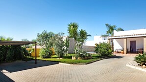 A courtyard with a paved walkway, a pergola, and various plants. - Vacation Home "Casa La Vigía" with Private Pool, Private Terraces & Wi-Fi (Conil de la Frontera)