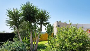 A garden with palm trees and a yellow wall. - Vacation Home "Casa La Vigía" with Private Pool, Private Terraces & Wi-Fi (Conil de la Frontera)
