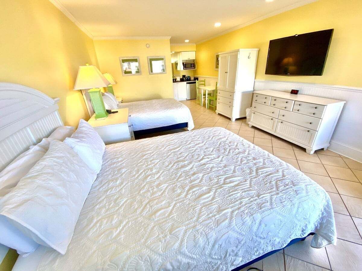 A hotel room with a large bed, a TV, a kitchenette, and a bathroom.