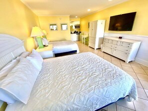 Ein Hotelzimmer mit einem großen Bett, einem Fernseher, einer Küchenzeile und einem Badezimmer.