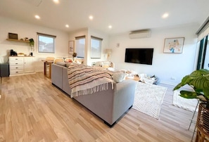 Relax in this spacious living room with a comfortable sofa, flat-screen TV, and dining area.