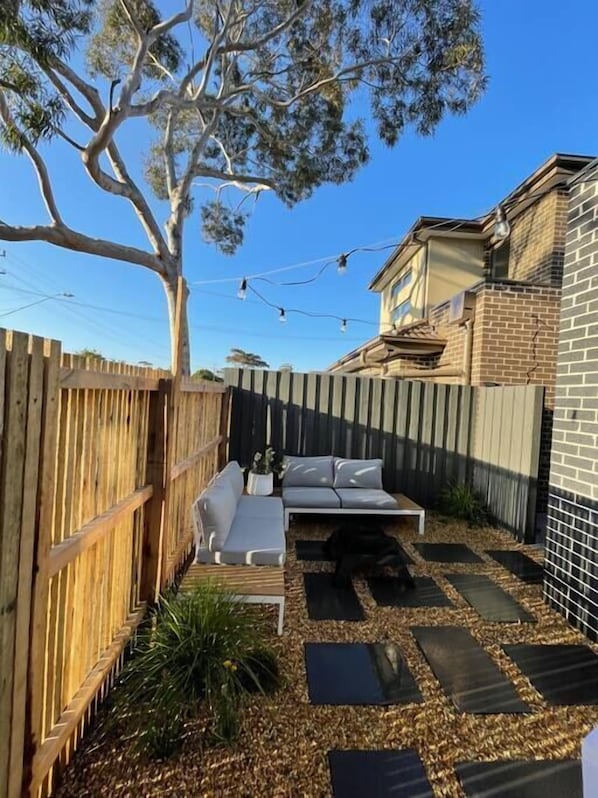 Relax in a serene outdoor space with a sofa, coffee table, and lush garden.