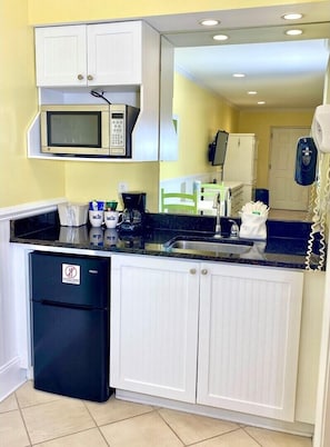 Compact kitchen with microwave, coffee maker, and refrigerator.