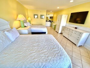 Une chambre d’hôtel avec un grand lit, un bureau, une chaise, une télévision et une kitchenette.