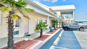 A hotel with a parking lot, palm trees, and a blue sky. - Pet-friendly, 3 Blocks to Beach, Pool, #105 (Atlantic Beach)