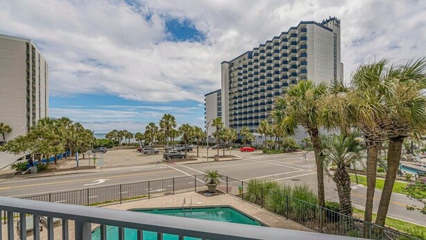 A hotel with a pool, palm trees, and a parking lot. - One Bedroom - Bluewater Villas 109A (Myrtle Beach)