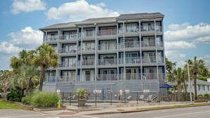 A multi-story hotel with balconies, a parking lot, and palm trees. - One Bedroom - Bluewater Villas 109A (Myrtle Beach)