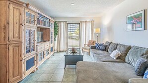 A living room with a sofa, a coffee table, and wooden cabinets. - One Bedroom - Bluewater Villas 109A (Myrtle Beach)