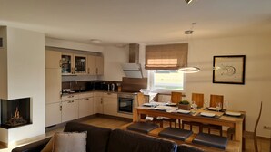 Eine moderne Küche mit Essbereich, Kamin und großem Fenster.