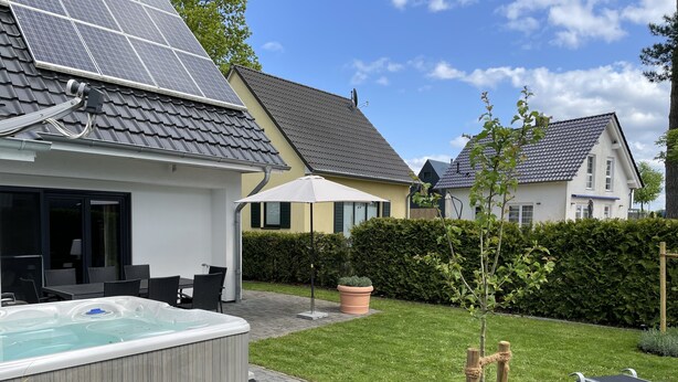 Ein Wohnhaus mit Solaranlage, Whirlpool, Sitzgelegenheit im Freien und einem gepflegten Rasen.