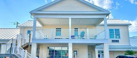 A two-story building with a balcony, a covered porch, and a staircase leading to the upper floor.