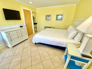 Une chambre à coucher avec un lit, une commode, une télévision, un four à micro-ondes et une porte.