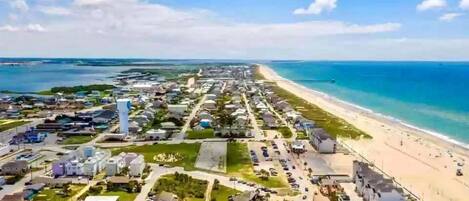 Vista aérea de un pueblo costero con playa, calles y edificios.