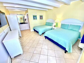 Une chambre avec deux lits, une petite kitchenette et une salle de bain.