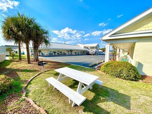 A picnic table in a grassy area with a building in the background.