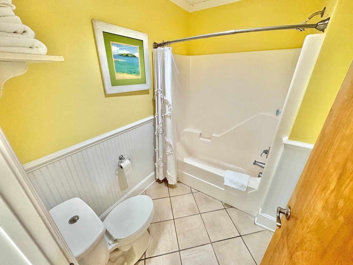 Une salle de bain équipée d’une baignoire, de toilettes et d’un rideau de douche.