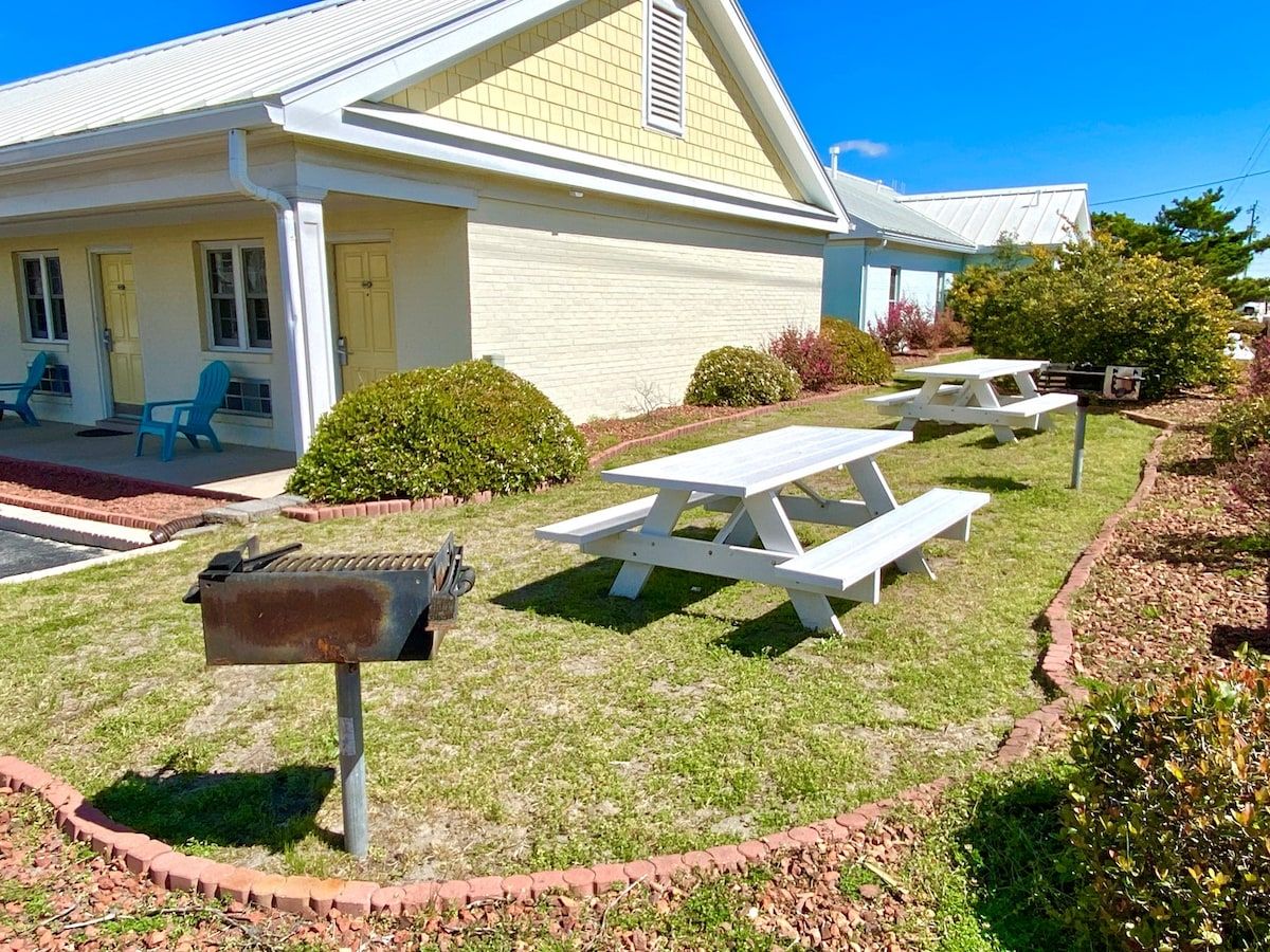 A house with a front porch, a mailbox, and two picnic tables.