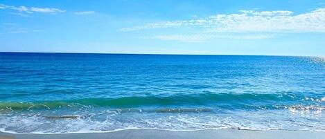 A beach with clear blue water and a sandy shore.
