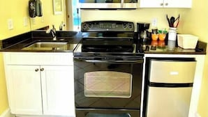 A kitchen with white cabinets, a black stove, a microwave, and a refrigerator. - Pet-friendly, 3 Blocks to Beach, Pool, #405 (Atlantic Beach)