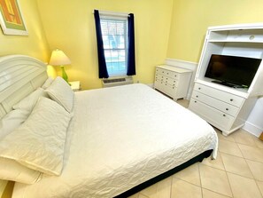 A bedroom with a bed, a dresser, a TV, and a window with curtains. - Pet-friendly, 3 Blocks to Beach, Pool, #501 (Atlantic Beach)