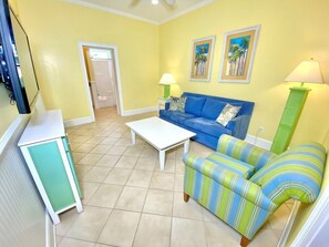 A living room with a sofa, a coffee table, a cabinet, and two wall-mounted lamps. - Pet-friendly, 3 Blocks to Beach, Pool, #501 (Atlantic Beach)