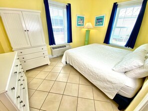 Ein Schlafzimmer mit einem Bett, einem Schminktisch, einem Kleiderschrank und einem Fenster mit Vorhängen.