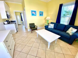 A compact living space with a kitchenette, a blue sofa, a white coffee table, and two framed pictures on the wall. - Pet-friendly, 3 Blocks to Beach, Pool, #504 (Atlantic Beach)