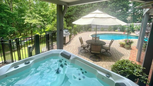 A hot tub in a covered outdoor area with a pool and patio furniture. - 2 BR Hidden Gem with Lake Access, Pool & Hot Tub 15 Min from Lanier Islands  (FLOWERY BRANCH)